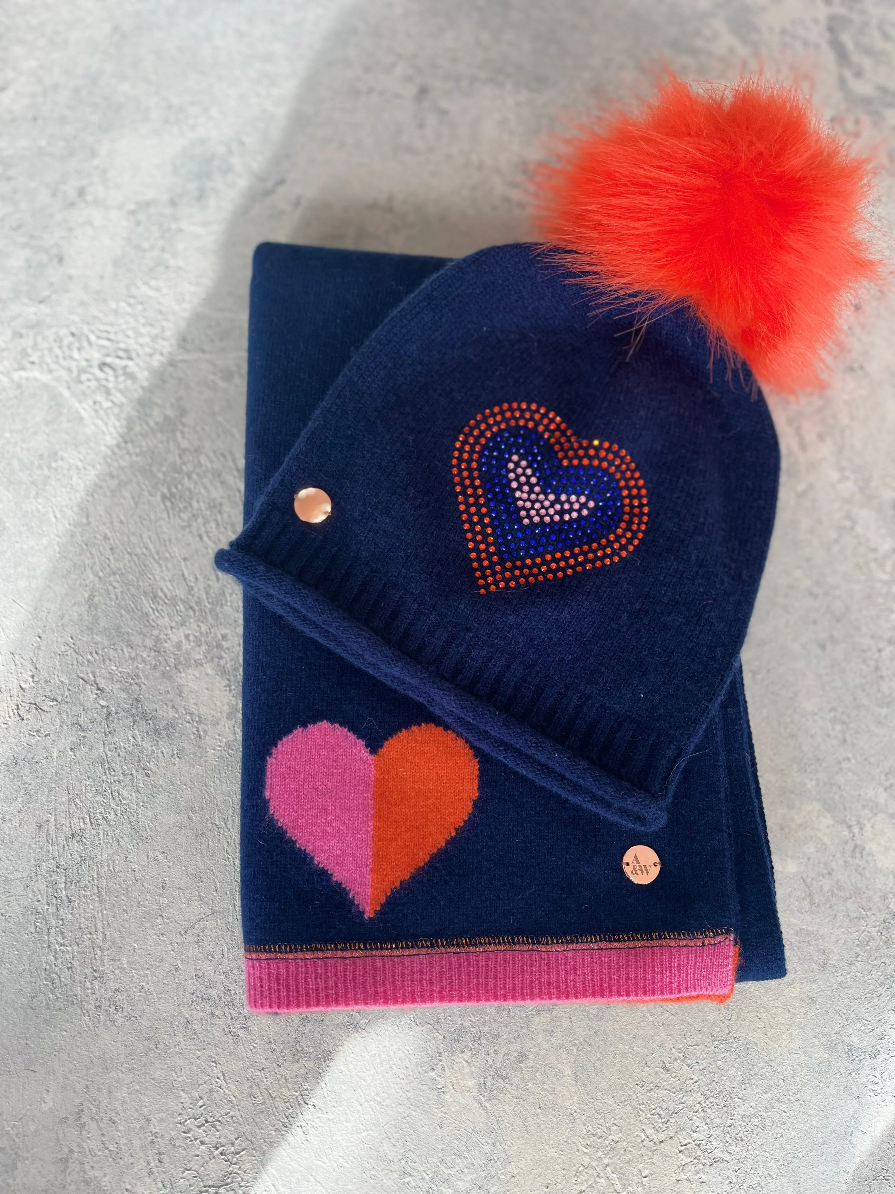 Navy cashmere plain knit beanie with heart embellishment & faux fur pom